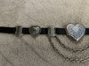 Black belt with heart-shaped metal buckles on a beige carpet
