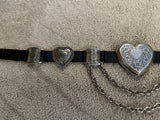 Black belt with heart-shaped metal buckles on a beige carpet